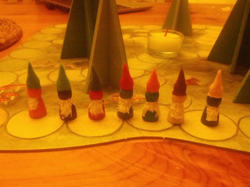 Small wooden pawn figures dressed in colourful caps and beards.