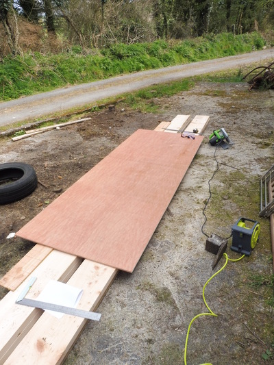 A long plywood board partly cut outside on the ground