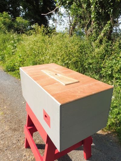 The hive with the roof off, showing seven covering panels and an additional panel with a feeding hole